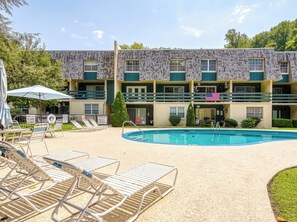A multi-story motel with a swimming pool, outdoor seating, and a flag. - Streamview Condo Pool, Wifi, Walking Distance to Gatlinburg (Gatlinburg)
