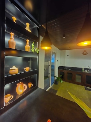 A modern kitchen with dark cabinetry, a wooden ceiling, and a glass door leading outside. - Lashi Dreams Ahangama (Ahangama)