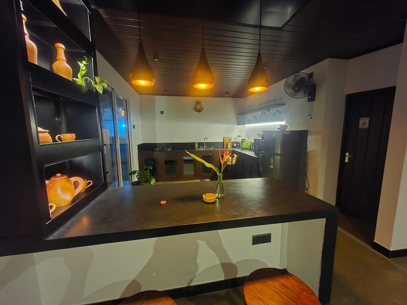 A modern kitchen with a central island, pendant lighting, and a view into the dining area.