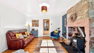 A cozy living room with a leather sofa, a blue armchair, and a stone fireplace.