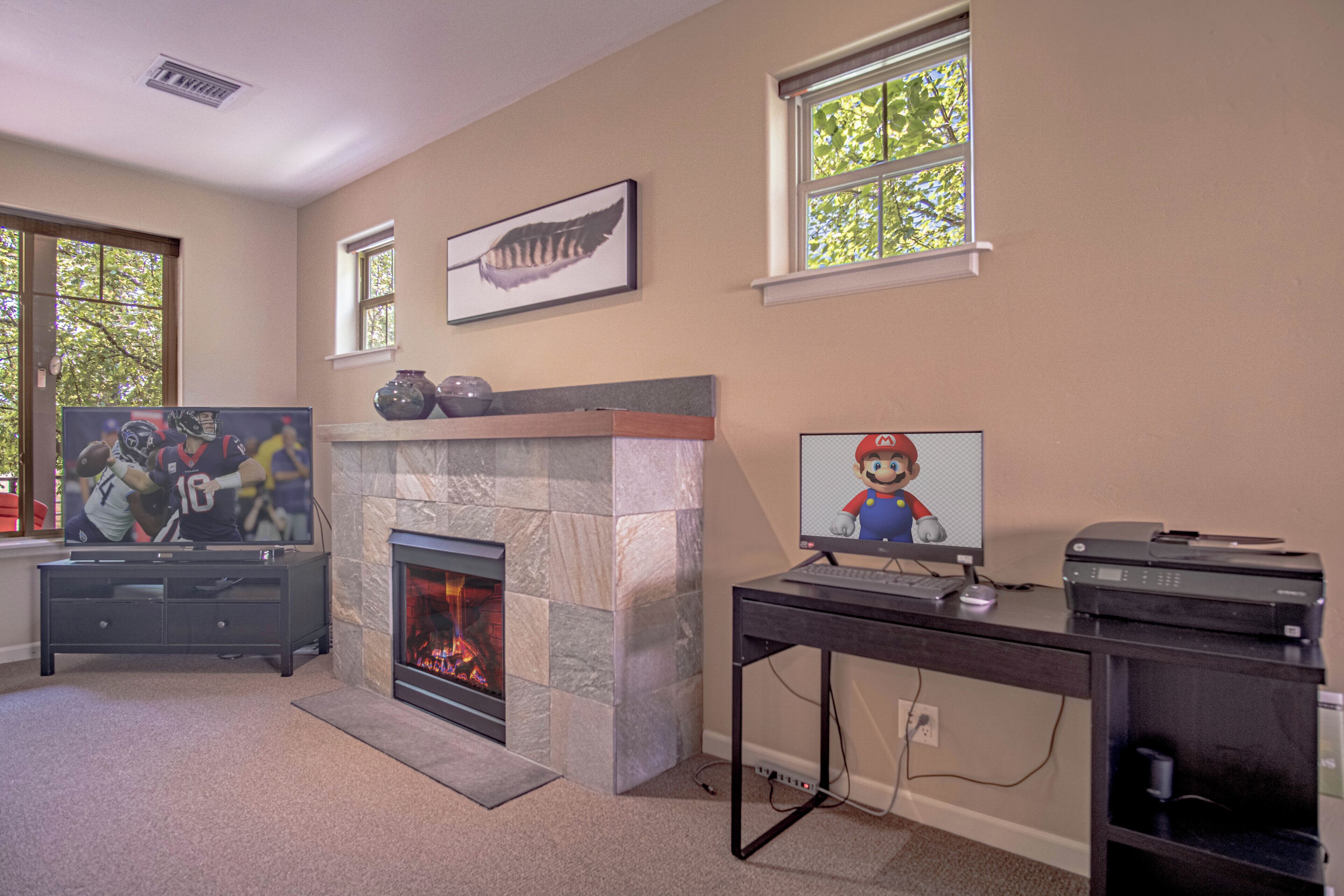 A living room with a fireplace, a television, and a gaming console.
