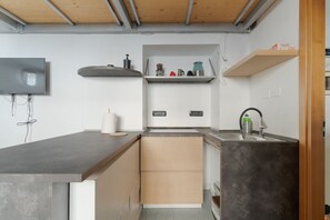 Uma cozinha compacta com máquina de lavar louça embutida, micro-ondas e pia.