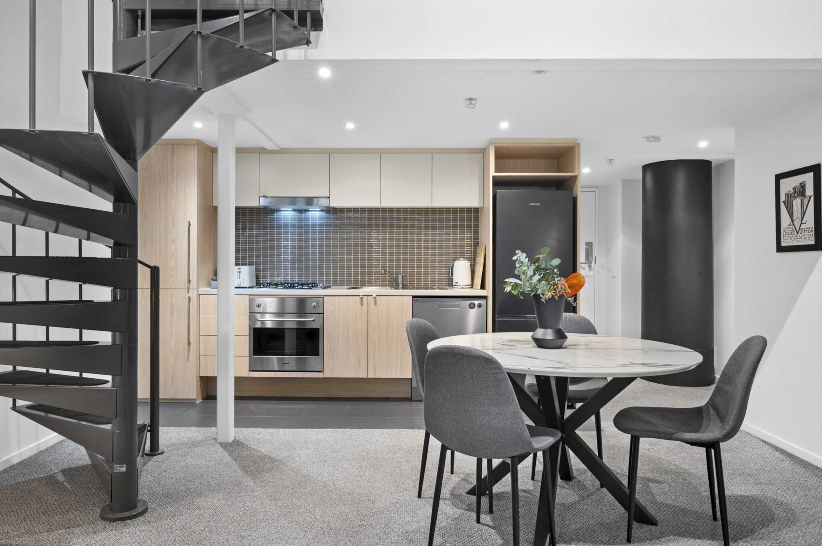 A modern kitchen with a central island, stainless steel appliances, and a dining area with a round table and chairs.