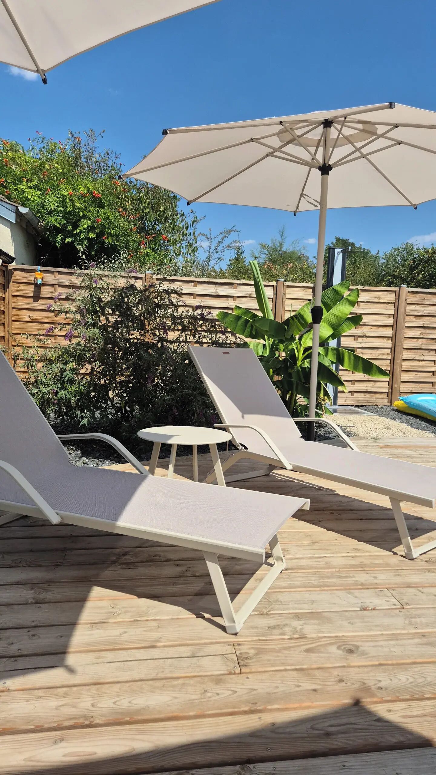 Een houten terras met lounge stoelen en een grote parasol voor schaduw.