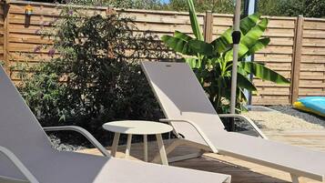 Een houten terras met lounge stoelen en een grote parasol voor schaduw.