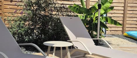 Terraza de madera con sillones de descanso y una sombrilla grande que proporciona sombra.