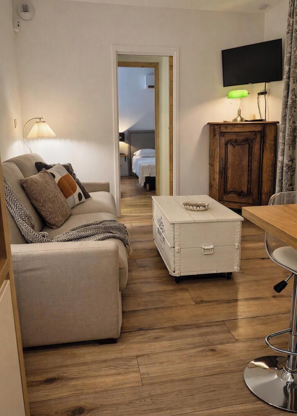 Een gemeubileerde woonkamer met een bank, een bijzettafeltje, een kast en een televisie.