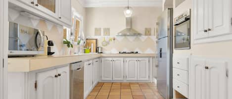 A kitchen with white cabinetry, a tiled floor, and a stainless steel range hood.