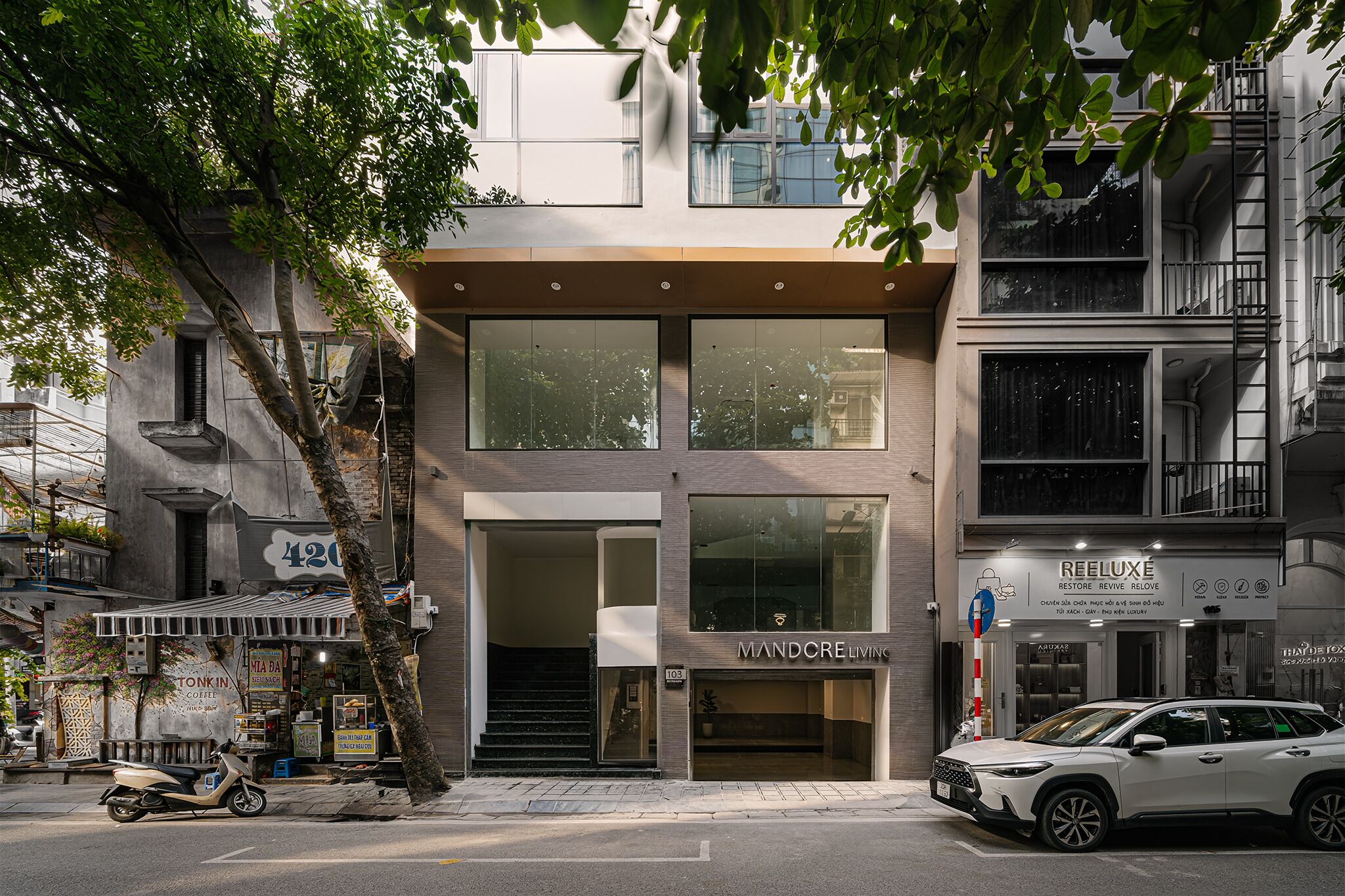 A modern building with large windows, a visible storefront, and a parked car.