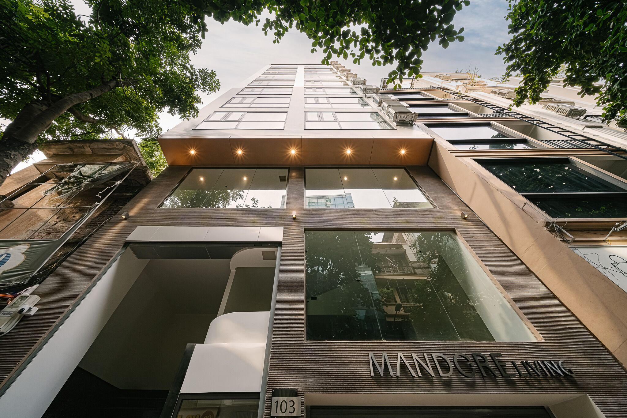 Een modern gebouw met een opvallende ingang, grote ramen en een bord met de tekst 'MANDCRFT'.