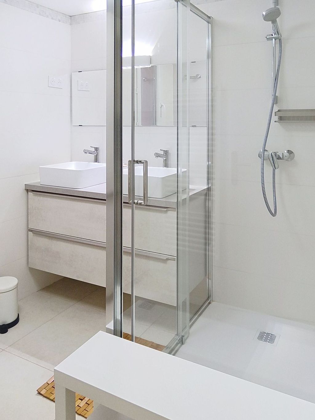 Une salle de bain moderne avec une douche à parois de verre, un lavabo blanc et un miroir.