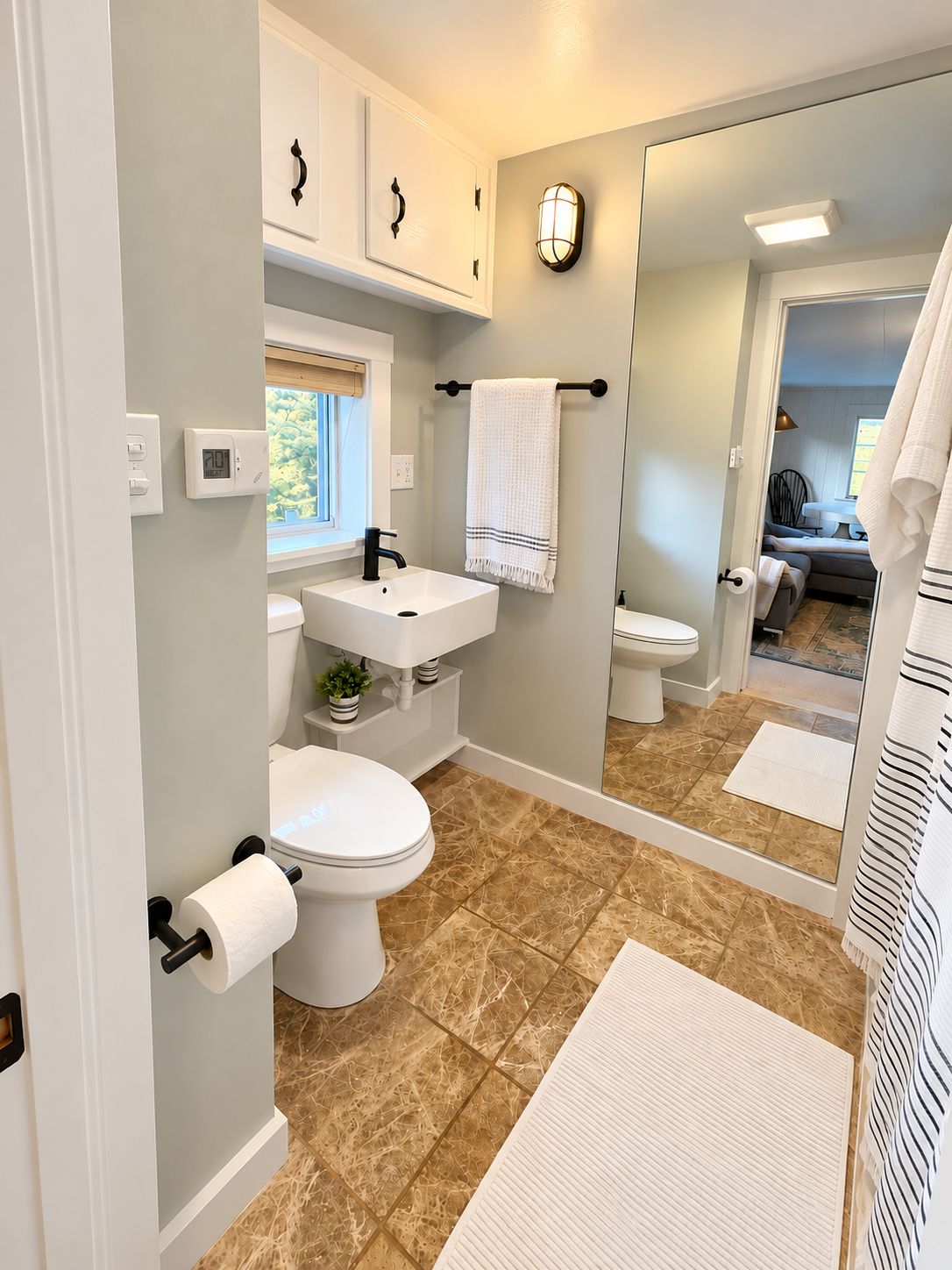 A bathroom with a toilet, sink, and mirror.