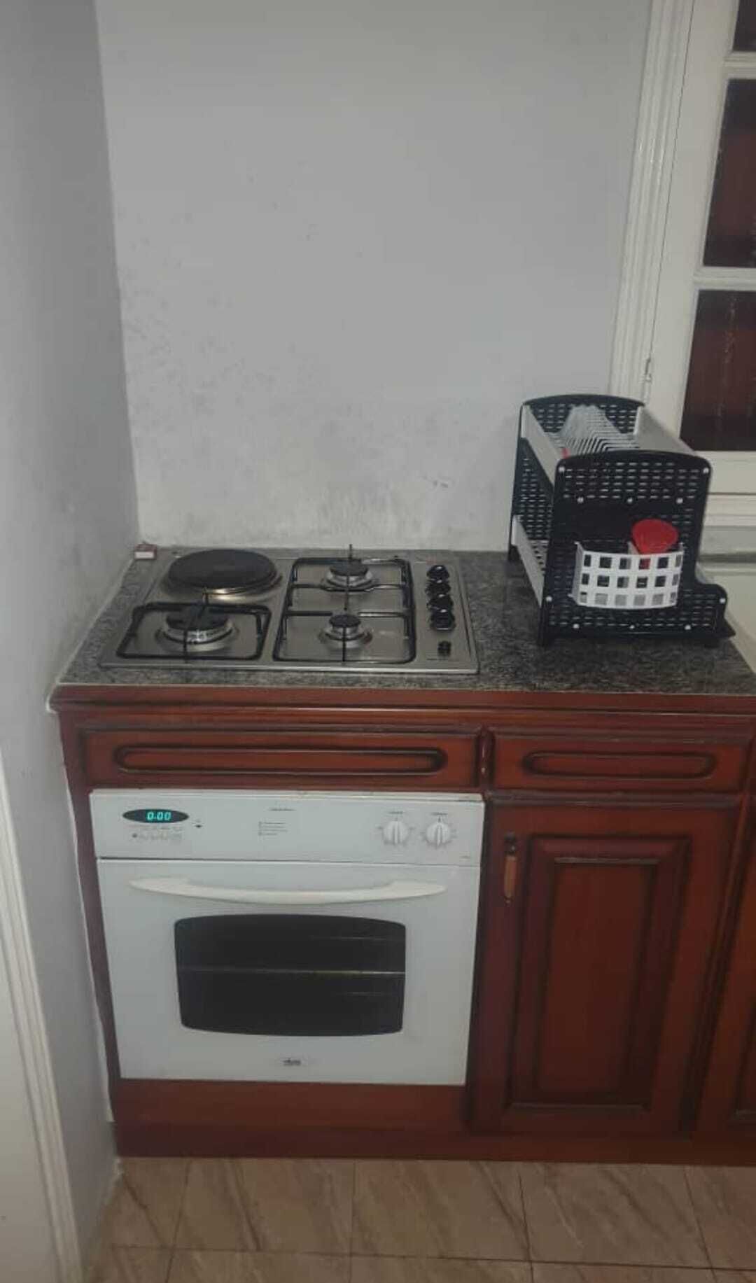 Een keuken met een gasfornuis, oven en een koffiezetapparaat op het aanrecht.