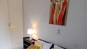 Una habitación de hotel con cama, mesitas de noche, lámpara y un cuadro en la pared.