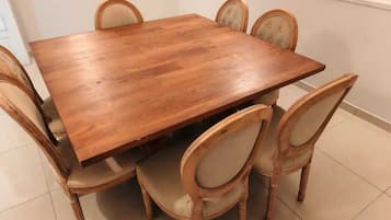 Uma mesa de jantar de madeira com seis cadeiras, cada uma com assento acolchoado e encosto curvo.