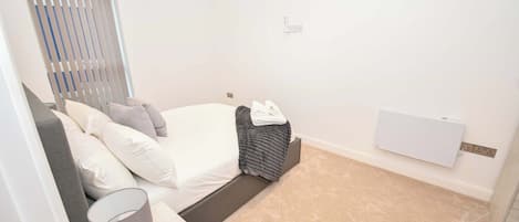 A bedroom with a bed, bedside table, lamp, and a radiator.