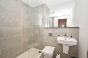 A modern bathroom with a glass-enclosed shower, a white toilet, and a sink with a mirror above it. - Your Home Away From Home in Central Leeds LS9 (Leeds)