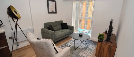A modern living room with a grey sofa, a round coffee table, a white armchair, and a wooden sideboard with a plant.