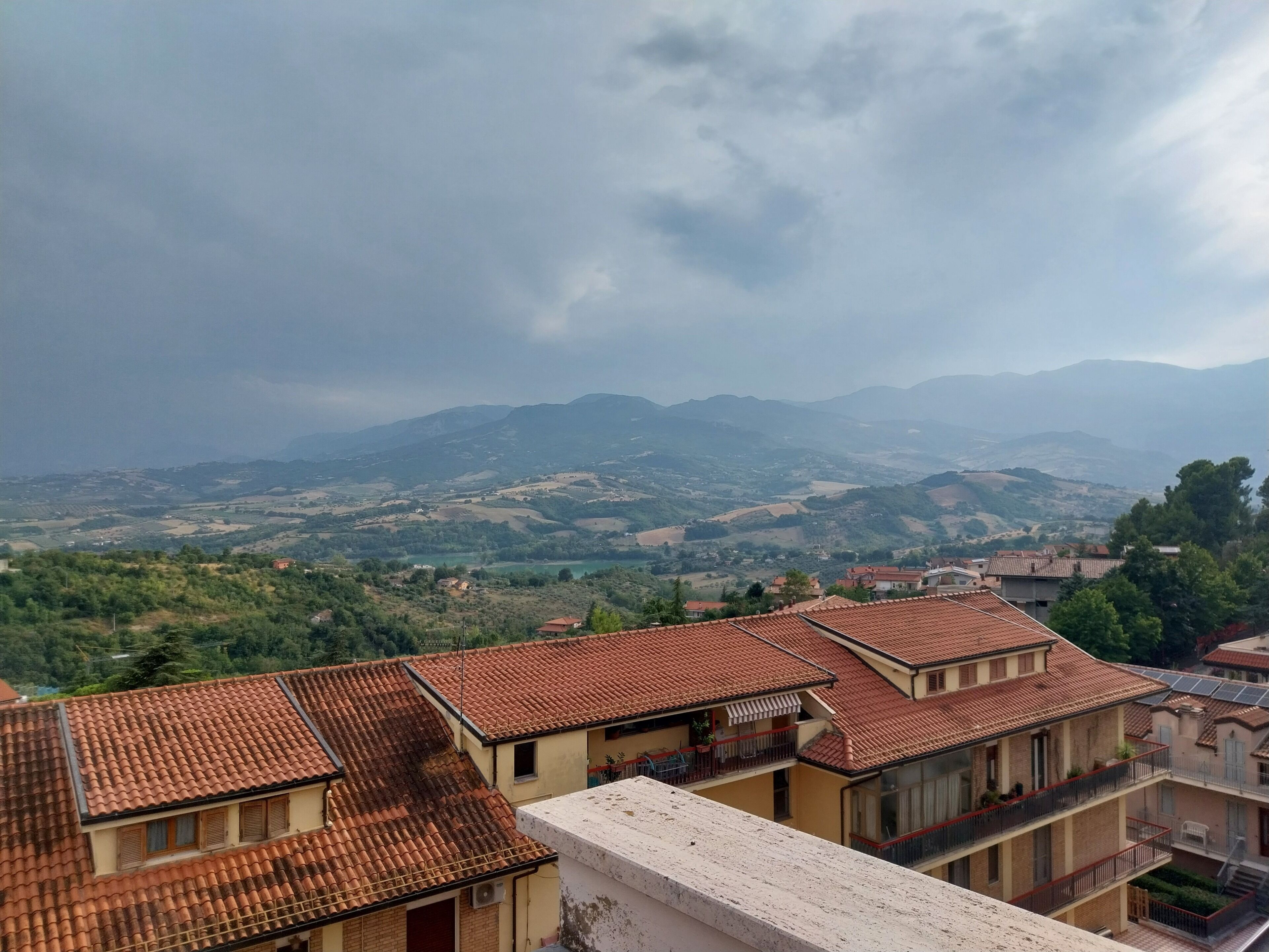 Un barrio residencial con tejados de tejas rojizas, un paisaje montañoso y montañas a lo lejos.