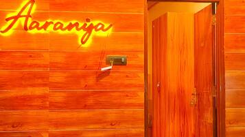 A wooden wall with a neon sign reading 'Aaranja' and a door leading to another room.