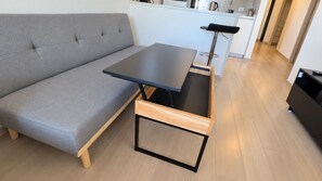 Un espace de vie moderne avec un canapé gris, une table à cadre en bois et un coin cuisine en arrière-plan.