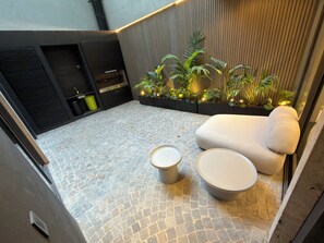 A modern outdoor seating area with a stone-tiled floor, a white sofa, and two round tables. - Plaza Italia: Luxury Building with Gym and Cowork (CABA)