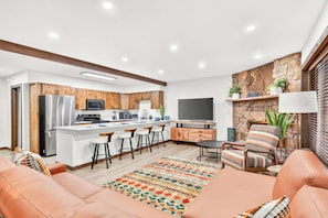 Een moderne keuken met een centraal kookeiland, barstoelen en een eethoek met een rug in een patroon.