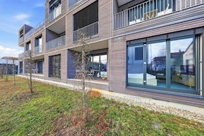 Een meerlaags woongebouw met balkons, grote ramen en een verzorgd gazon.