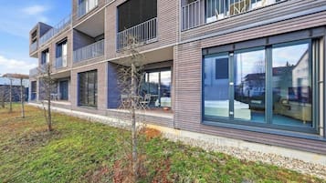 A multi-story residential building with balconies, large windows, and a well-maintained lawn.