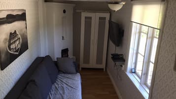 A room with a sofa, a television, a patterned wall, and a window.