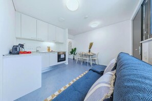 Un espacio habitable compacto con kitchenette, comedor y sofá.