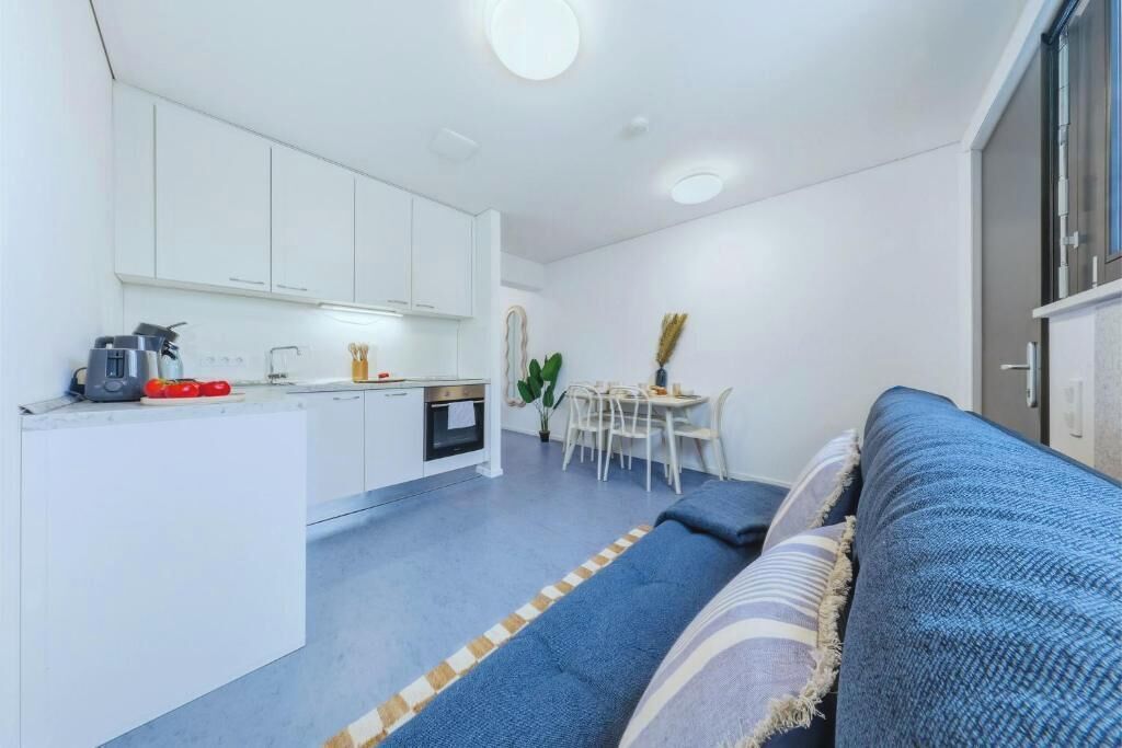 Un espacio habitable compacto con kitchenette, comedor y sofá.