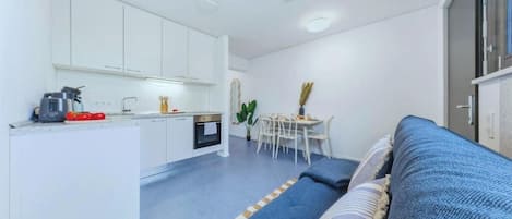 A compact living space with a kitchenette, a dining area, and a sofa.
