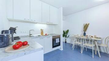 Eine moderne Küche mit weißen Schränken, einem eingebauten Backofen und einem Essbereich mit Tisch und Stühlen.