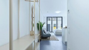 Ein modernes Interieur mit einem Flur, der in einen Wohnbereich führt, einer Couch und einer Pflanze.