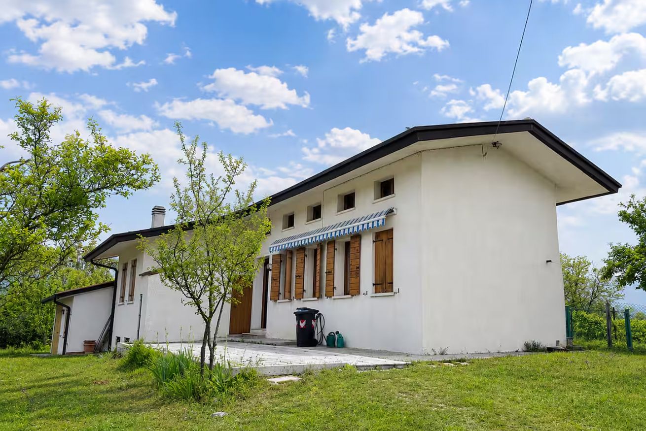 A single-story building with a flat roof, a porch with wooden shutters, and a small attached structure.