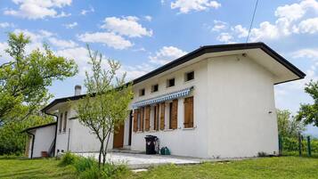 A single-story building with a flat roof, a porch with wooden shutters, and a small attached structure.