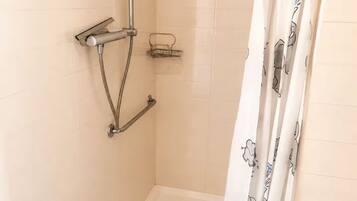 A shower area with a handheld showerhead, a wall-mounted towel rack, and a small shelf.
