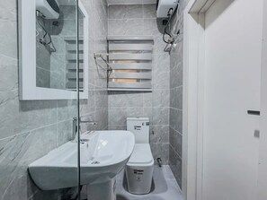 A modern bathroom with a white sink, toilet, and shower area. - Modern Studio Apartment in Victoria Island with Pool, Fast Wi-Fi & 24/7 Power (Lagos)