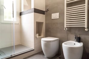 Ein modernes Badezimmer mit Duschkabine aus Glas, Toilette und Waschbecken mit Handtuchhalter.