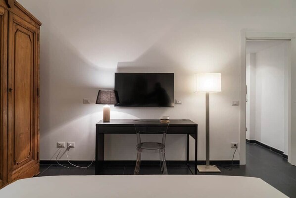 Ein Hotelzimmer mit einem Bett, einem Schreibtisch mit Stuhl, einem Fernseher und einer Lampe.
