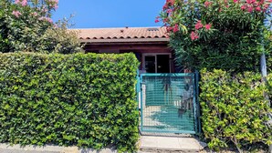 Ein Haus mit Ziegeldach, einem Metalltor und dichten, grünen Hecken.