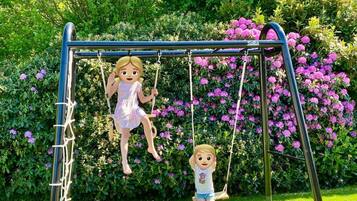 A swing set in a garden with lush greenery and flowers.