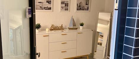 A room with a white dresser, a small sailboat model, and a wall with black and white photos.