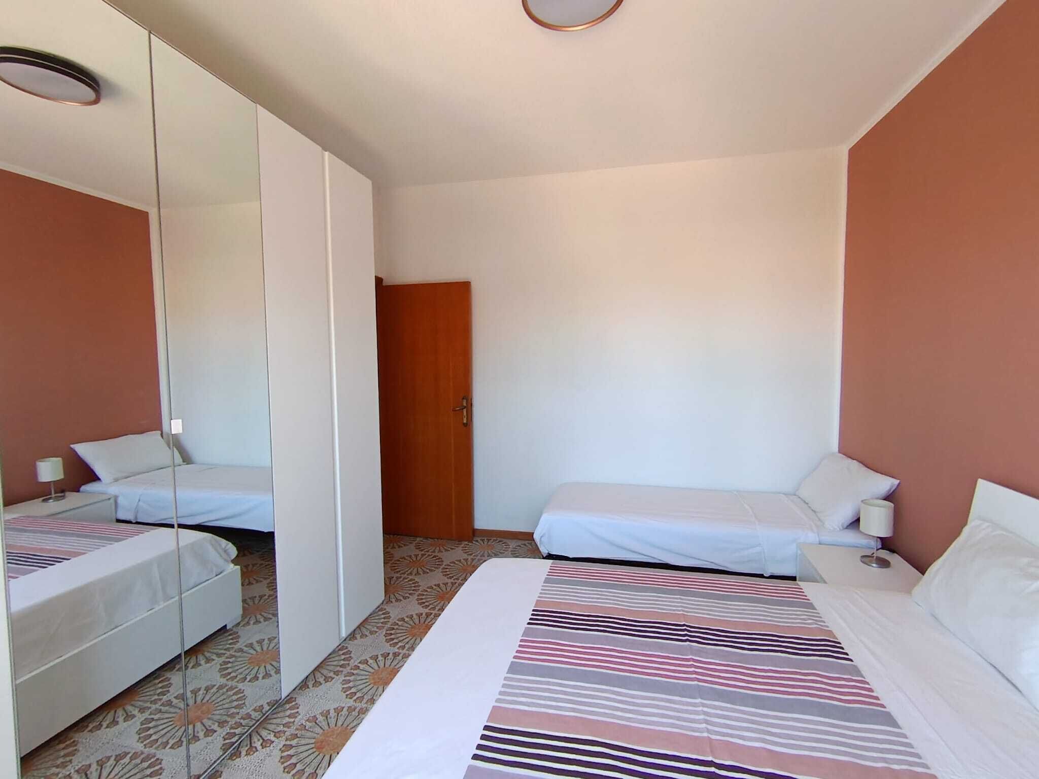 Une chambre d’hôtel avec deux lits, un grand miroir, une porte et une moquette à motifs.