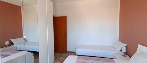 Une chambre d’hôtel avec deux lits, un grand miroir, une porte et une moquette à motifs.