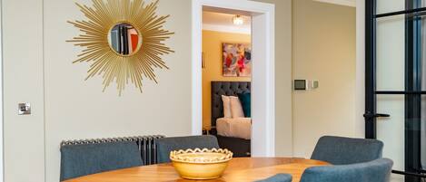 A dining area with a round table, chairs, and a decorative sunburst mirror.