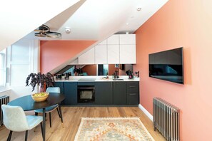 Eine moderne Küche mit Essbereich, einem an der Wand befestigten Fernseher und einem großen Fenster für natürliches Licht.