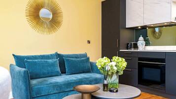 A modern living room with a blue sofa, a round coffee table, and a decorative mirror on the wall.
