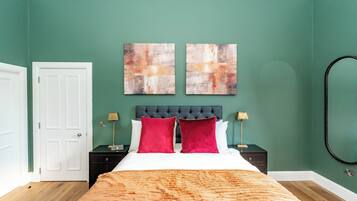 A bedroom with a bed, two bedside tables, a headboard, and two abstract paintings on the wall.